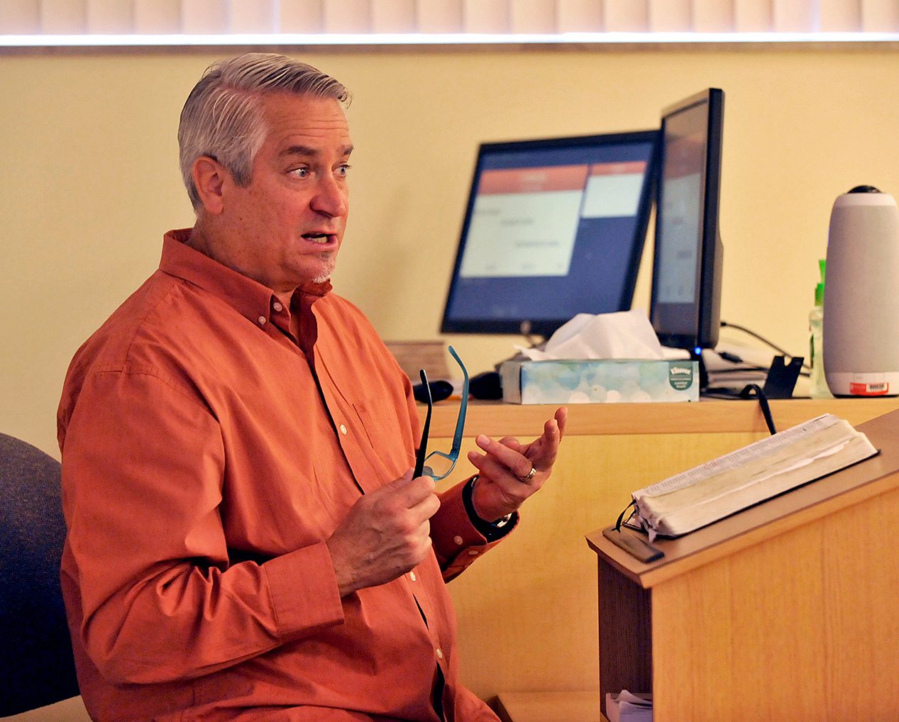 professor Joel Soza seated behind lectern with open Bible
