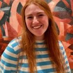 Elizabeth Rayl smiling broadly in front of geometric art on wall
