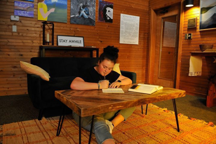 female student seated on floor, writing at low table