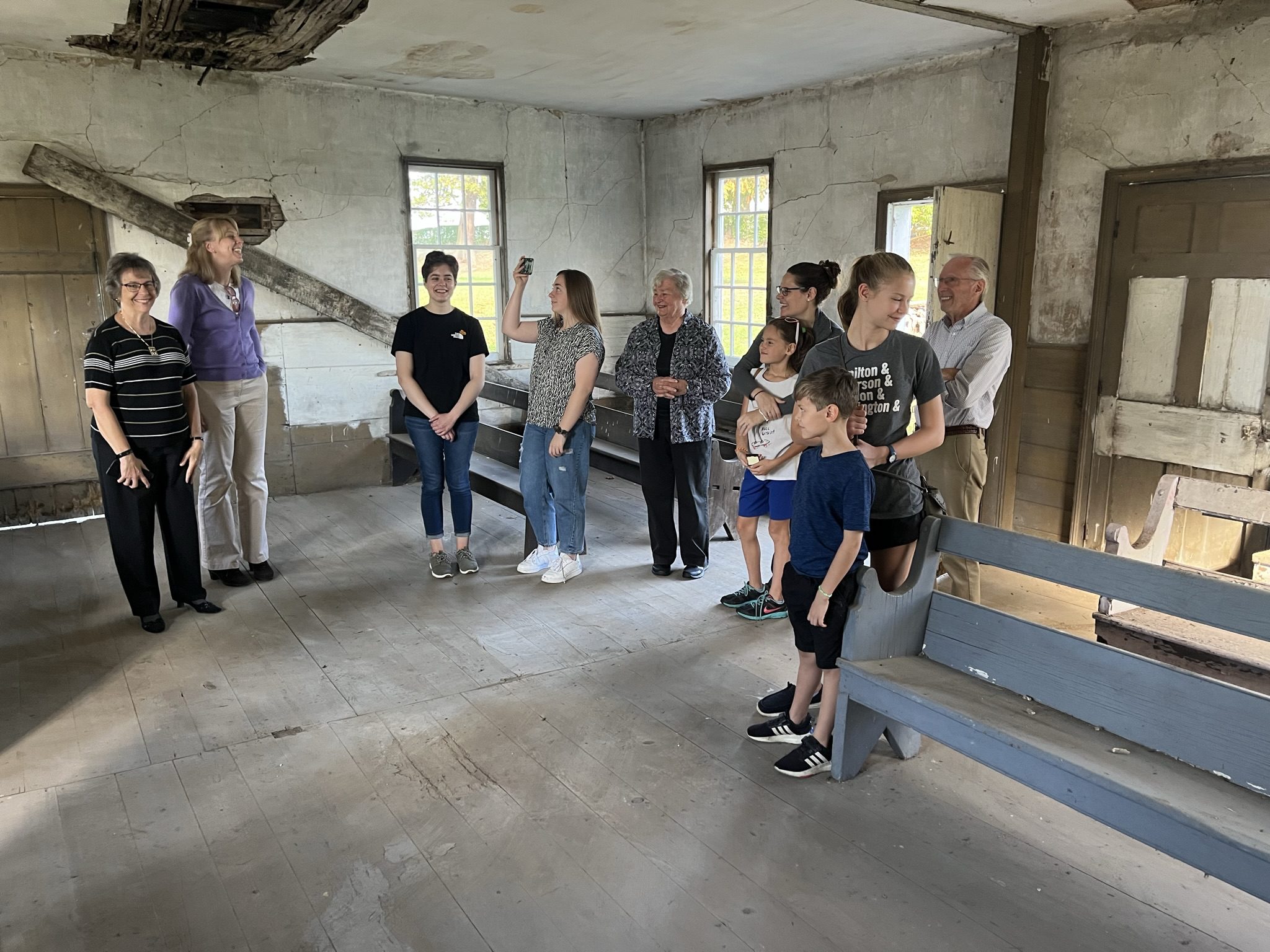 mixed age group of 10 people inside a rustic, historic building