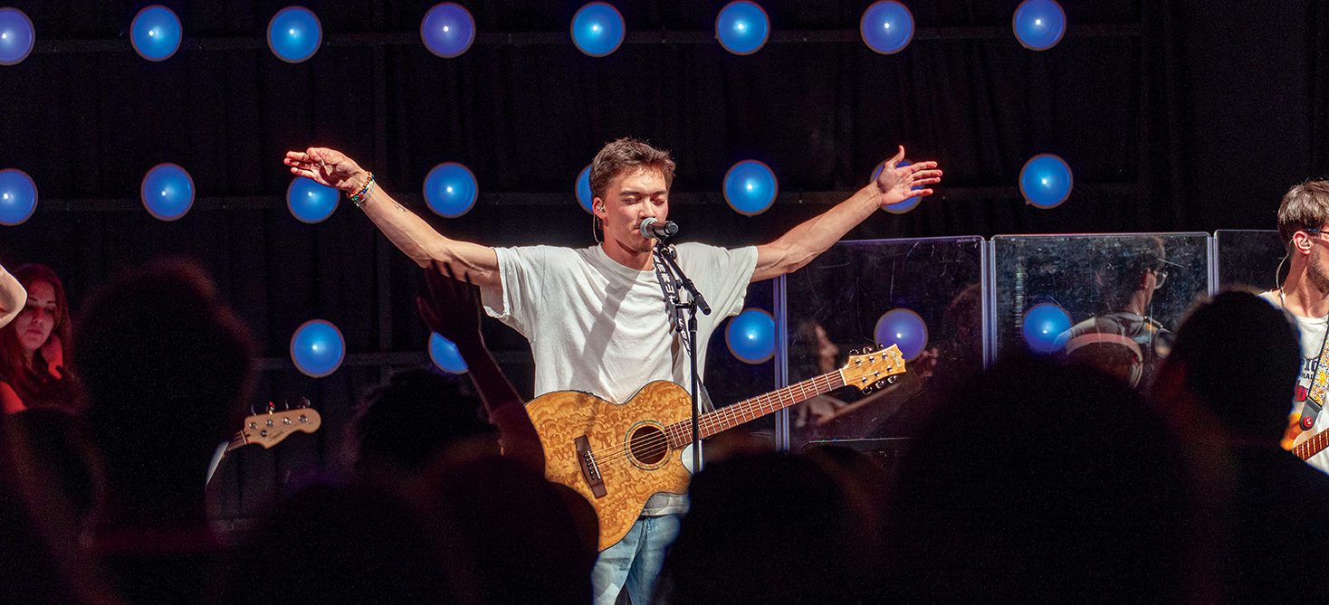 male student in front of mic with arms outstretched