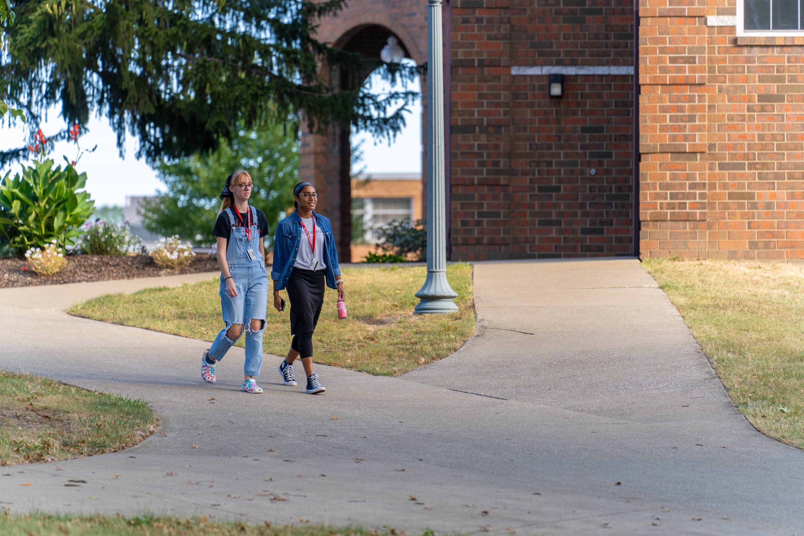 close-up view of 2 female students wearing denim, walking away from Heritage Hall