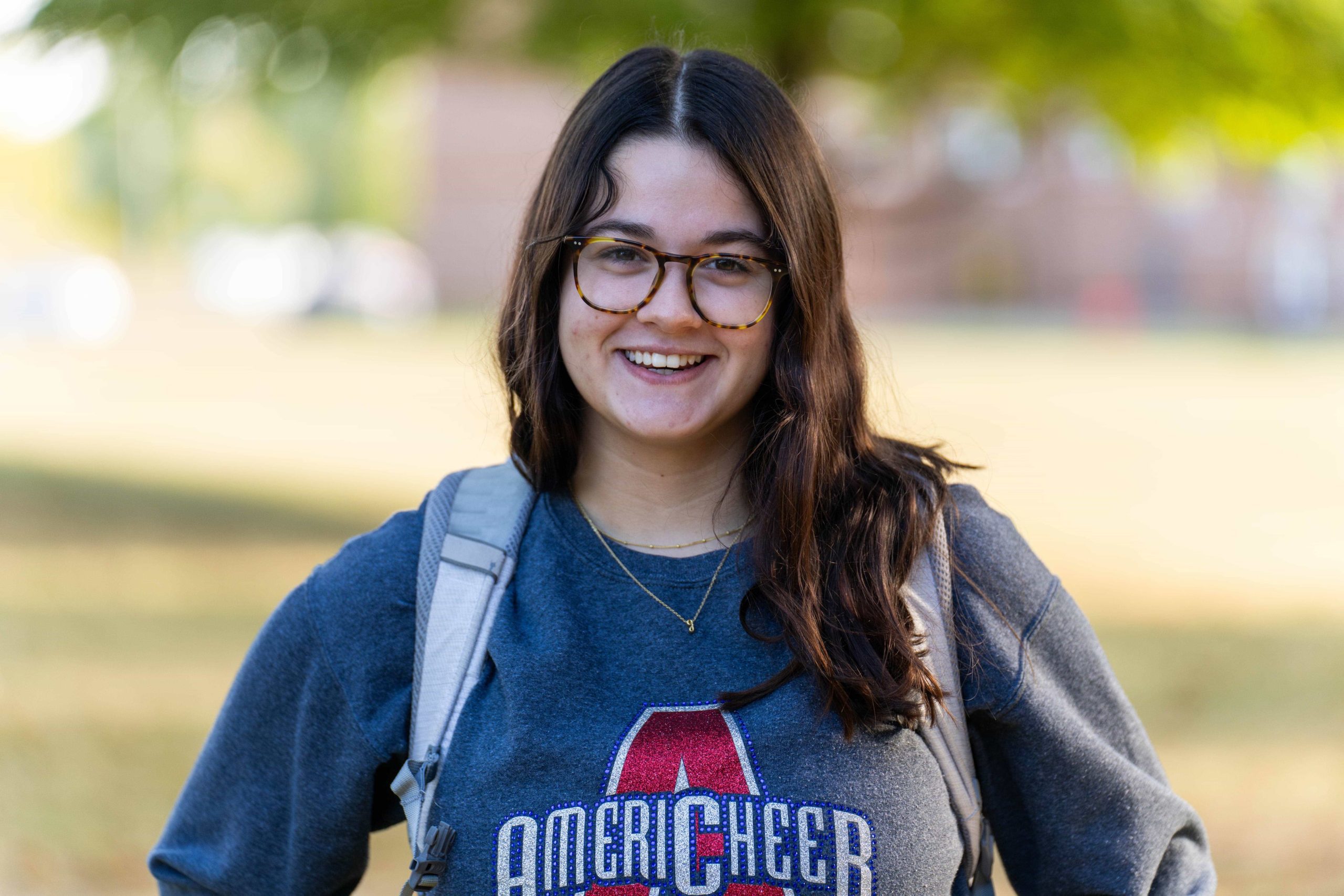 female brown-haired student wearing glasses and smiling at camera