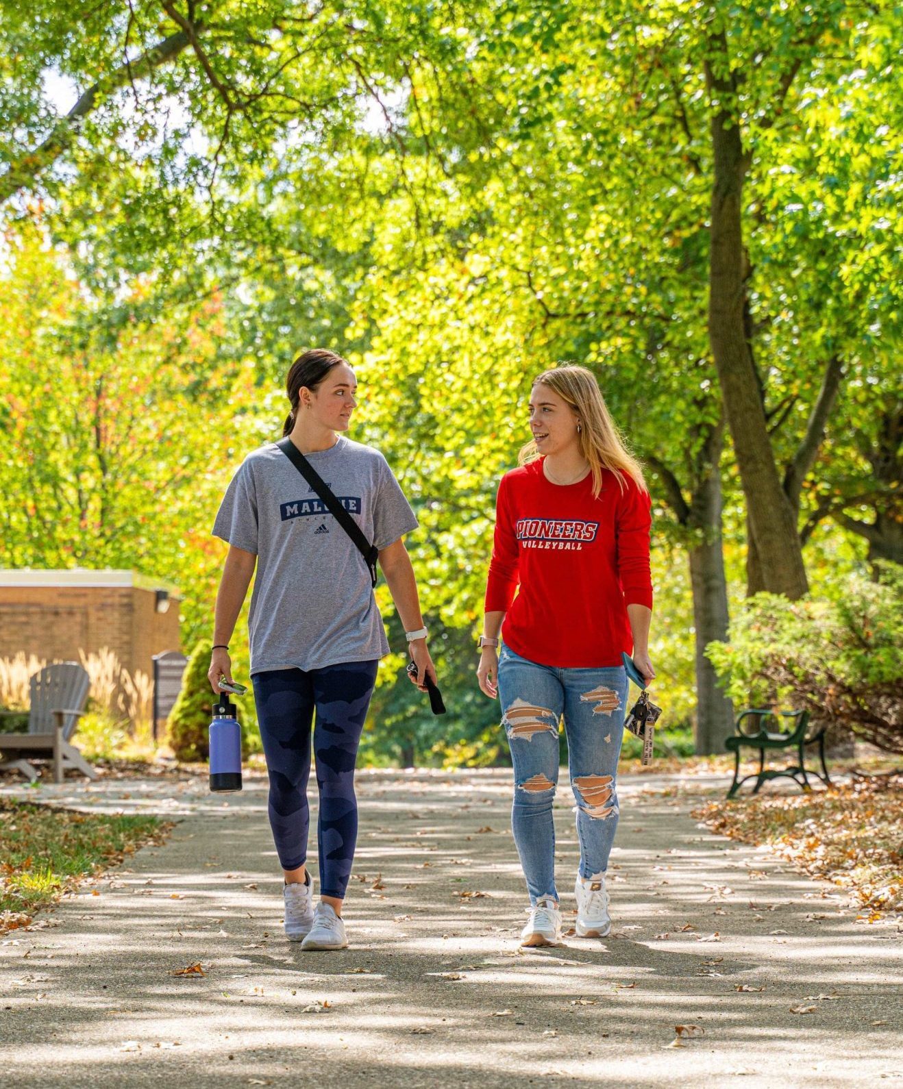 2 tall female students walking on sidewalk