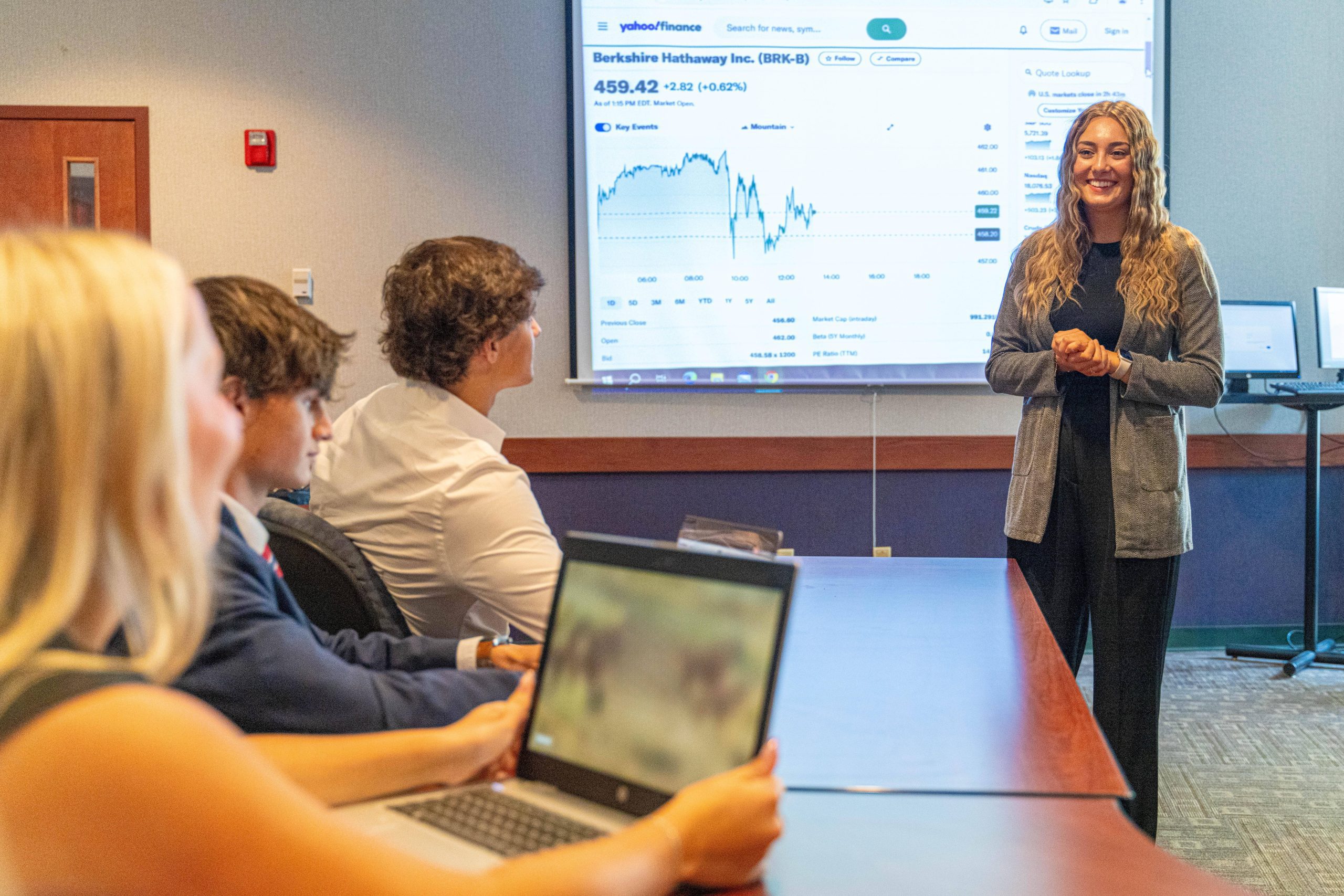 Female in front of screen; other students in foreground