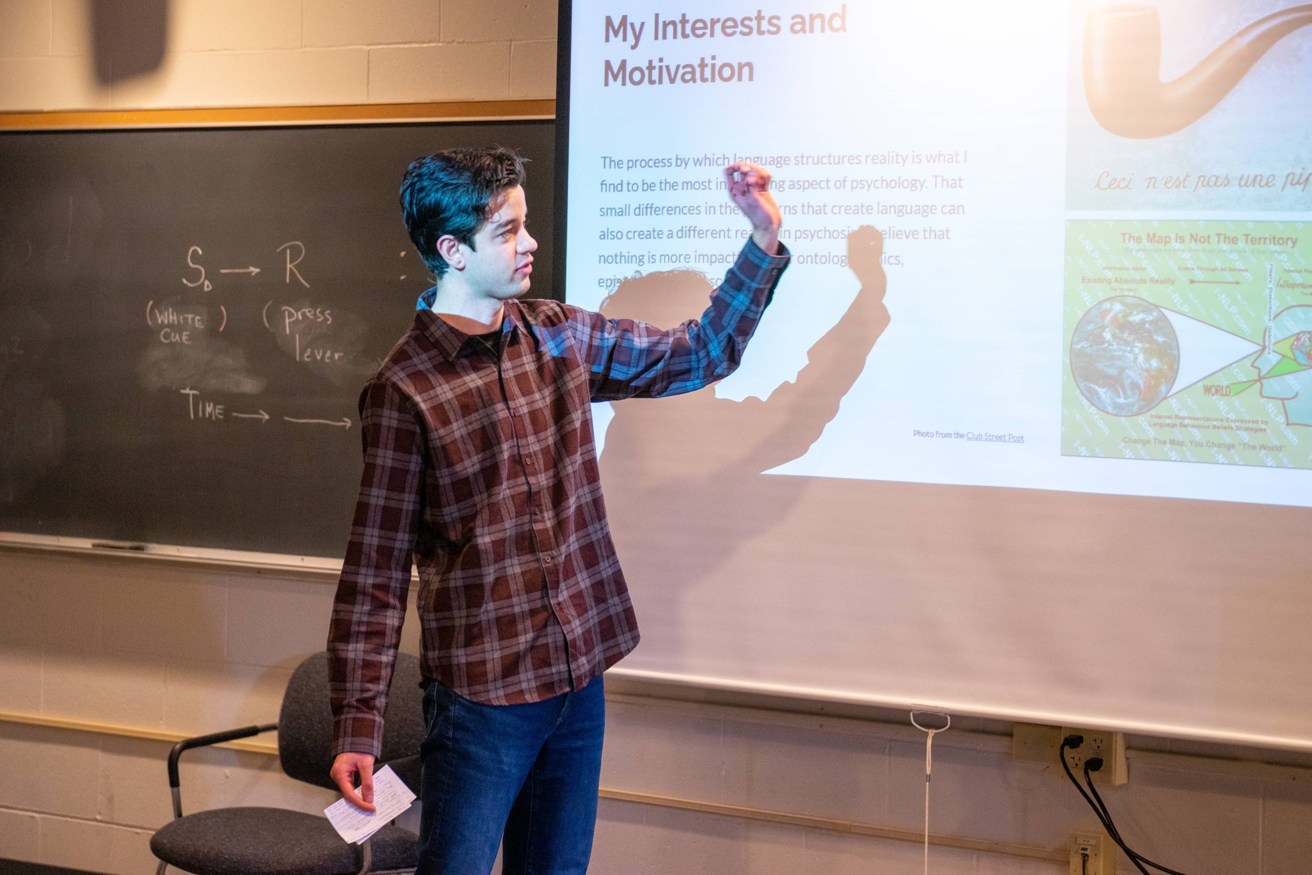 male student gesturing toward image on projector screen