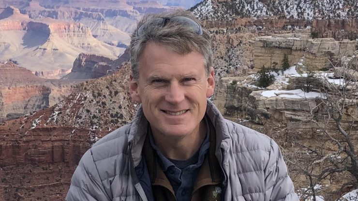 Chuck Hoover in parka with rough, beautiful terrain in background