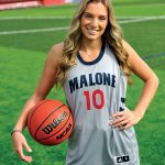 Female student with long hair stands outside in a Malone basketball uniform with basketball