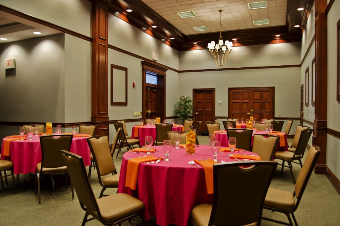 Room at Malone set up for an event with round tables covered in red tablecloths.