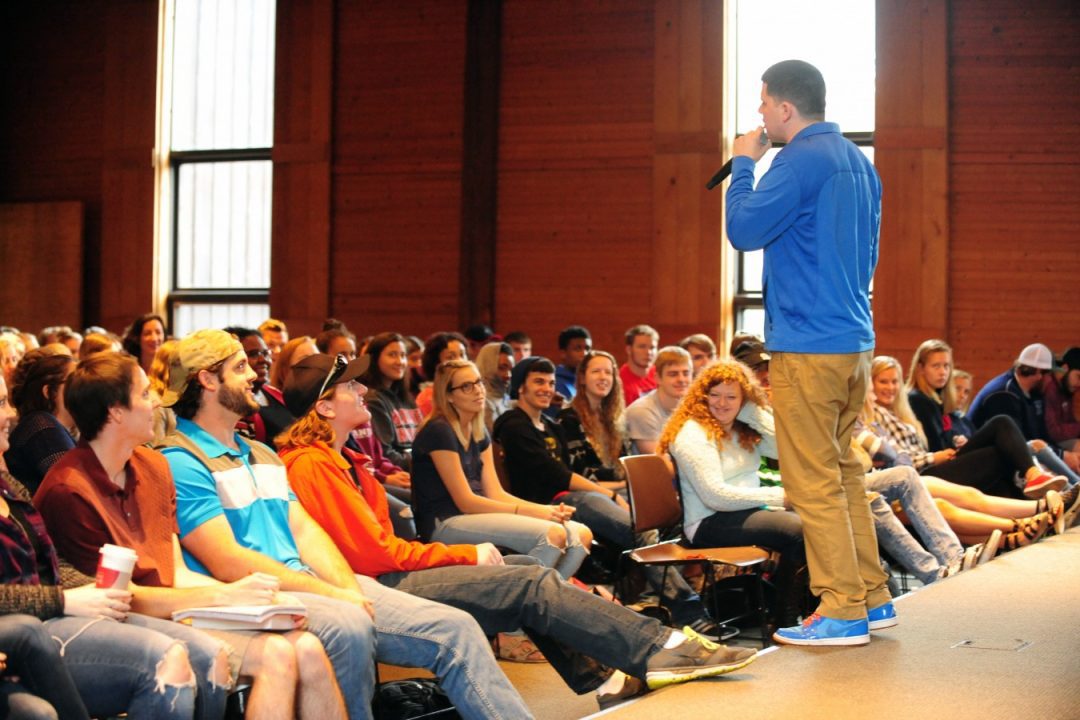 Event at Malone showing a speaker on stage talking to a large seated group