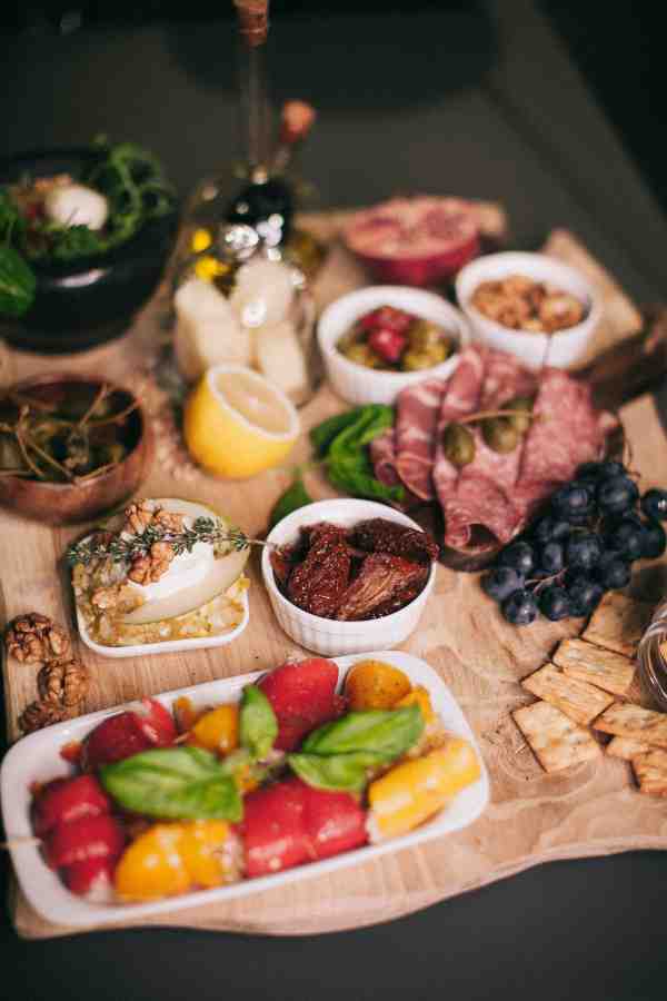 an image of a charcuterie board consisting of tasty foods including fruit, salami, and crackers