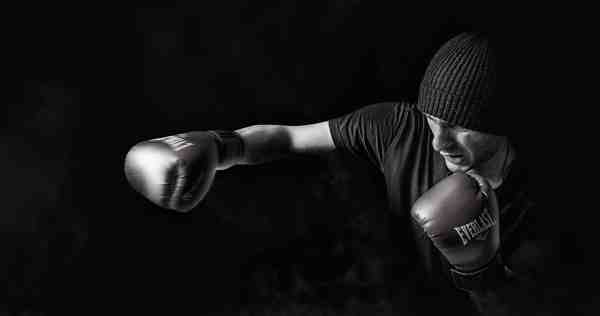 black and white image of a boxer with boxing gloves on taking a right swing
