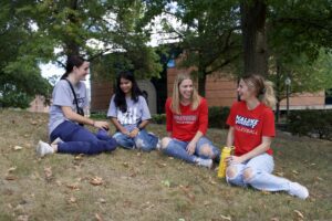 Four Malone Students sitting outside the library.